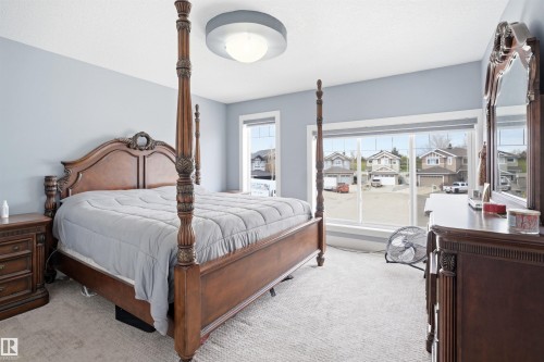 Spacious interior room featuring light blue painted walls, carpeted flooring, and a large window providing natural illumination - 3909 49 Ave, Beaumont, AB - Indoor Photo Showing Bedroom