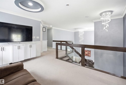 Upper-level landing featuring a built-in media console with white cabinetry, recessed lighting, and a contemporary chandelier - 3909 49 Ave, Beaumont, AB - Indoor