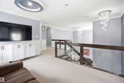 Upper-level landing featuring a built-in media console with white cabinetry, recessed lighting, and a contemporary chandelier - 