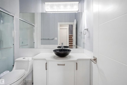 Contemporary bathroom featuring a black vessel sink, white vanity with storage, oversized mirror, and a glass-enclosed shower - 3909 49 Ave, Beaumont, AB - Indoor