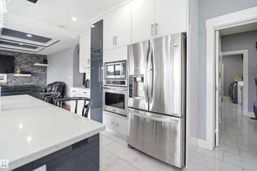 Modern kitchen featuring white and dark gray cabinetry, stainless steel appliances, a built-in microwave, a built-in oven, and a white countertop - 3909 49 Ave, Beaumont, AB - Indoor Photo Showing Kitchen With Upgraded Kitchen