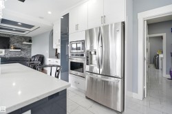 Modern kitchen featuring white and dark gray cabinetry, stainless steel appliances, a built-in microwave, a built-in oven, and a white countertop - 