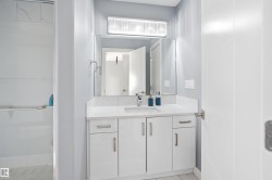 Contemporary bathroom featuring a white vanity with integrated sink, quartz countertop, and a large mirror with overhead lighting - 