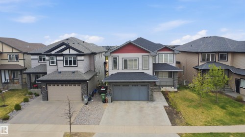 Contemporary exterior featuring light grey siding, a dark grey shingle roof, and red accent gables - 3909 49 Ave, Beaumont, AB - Outdoor With Facade