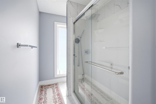 Glass-enclosed shower with a rainfall showerhead, handheld sprayer, and built-in shelving - 3909 49 Ave, Beaumont, AB - Indoor Photo Showing Bathroom