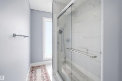 Glass-enclosed shower with a rainfall showerhead, handheld sprayer, and built-in shelving - 