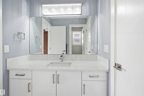 Contemporary vanity featuring white cabinetry with brushed nickel hardware, an undermount sink, and a spacious countertop - 3909 49 Ave, Beaumont, AB - Indoor Photo Showing Bathroom