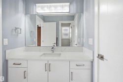 Contemporary vanity featuring white cabinetry with brushed nickel hardware, an undermount sink, and a spacious countertop - 
