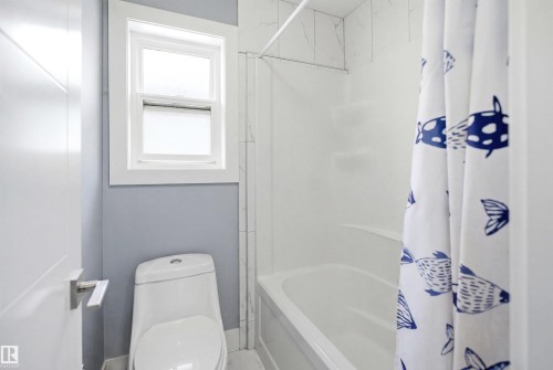 Bathroom featuring a built-in tub with a white surround, white wall tile, and a single window with white trim - 3909 49 Ave, Beaumont, AB - Indoor Photo Showing Bathroom