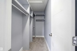 Walk-in closet featuring built-in shelving, hanging rods, and light gray wall tones - 