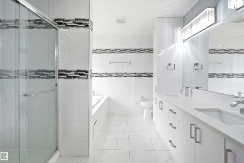 Contemporary bathroom featuring a glass-enclosed shower, dual vanity with undermount sinks, and a built-in bathtub - 3909 49 Ave, Beaumont, AB - Indoor Photo Showing Bathroom