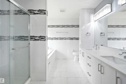 Contemporary bathroom featuring a glass-enclosed shower, dual vanity with undermount sinks, and a built-in bathtub - 