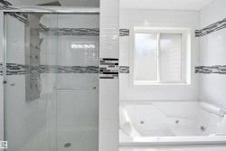 Modern bathroom featuring a glass-enclosed shower with a multi-jet panel, a jetted soaking tub, white tiled walls with decorative mosaic accents, and a frosted glass window - 