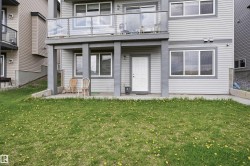 Ground-level patio with a white entry door, multiple windows, and a glass-paneled balcony overhead - 