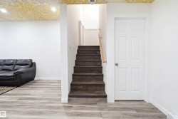 Staircase with wood-finish treads and light wood handrail, featuring white trim and a white paneled door - 