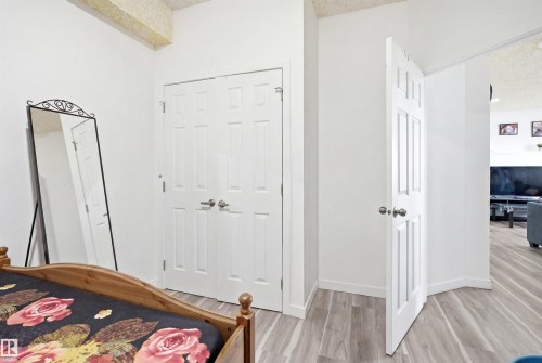 BASEMENT ROOM 2- Recessed closet with paneled bifold doors, complementing a six-panel interior door and light wood-finish flooring - 3909 49 Ave, Beaumont, AB - Indoor