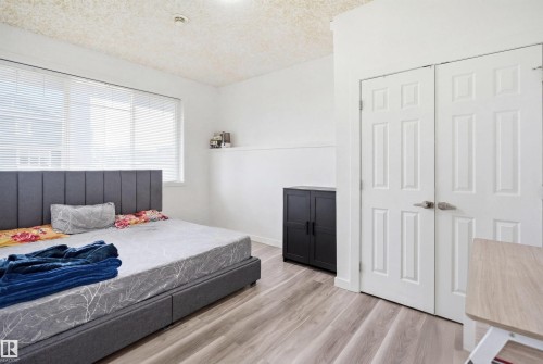 Room featuring a wide window with blinds, light wood-finish flooring, and white paneled doors - 3909 49 Ave, Beaumont, AB - Indoor Photo Showing Bedroom