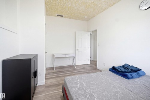 Spacious room featuring light wood-finish flooring, white walls, and a textured acoustic ceiling - 3909 49 Ave, Beaumont, AB - Indoor Photo Showing Bedroom