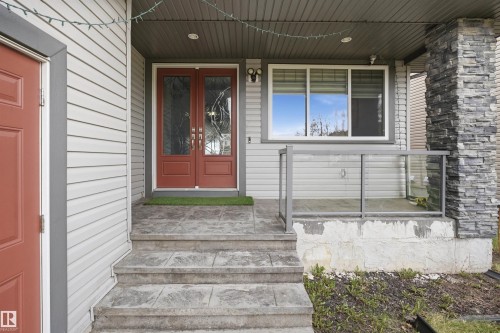 Exterior featuring light-colored siding and a stone-clad pillar - 3909 49 Ave, Beaumont, AB - Outdoor With Deck Patio Veranda