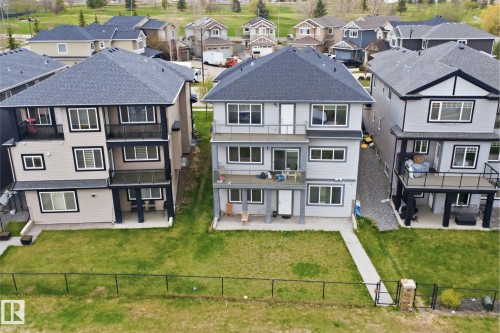 Contemporary three-story residence featuring multiple balconies with black railings, a grass lawn, and a concrete pathway - 3909 49 Ave, Beaumont, AB - Outdoor With Facade