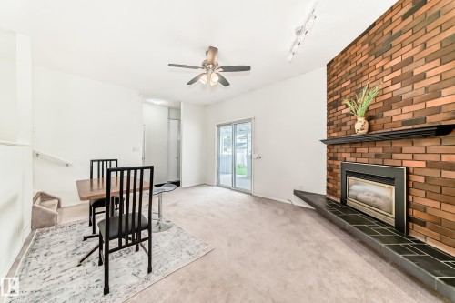 Living space featuring a brick accent wall with an integrated fireplace, a dark mantel, and a tiled hearth - 14123 96 Street, Edmonton, AB 