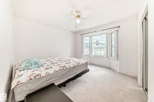 Room featuring a multi-panel bay window, light-colored carpeting, a ceiling fan with integrated lighting, and a sliding door with a mirrored panel - 14123 96 Street, Edmonton, AB 