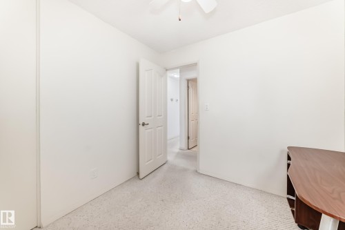 Neutral tone carpet flooring, white walls, white ceiling fan with light fixture, and a white paneled door with silver hardware - 14123 96 Street, Edmonton, AB 