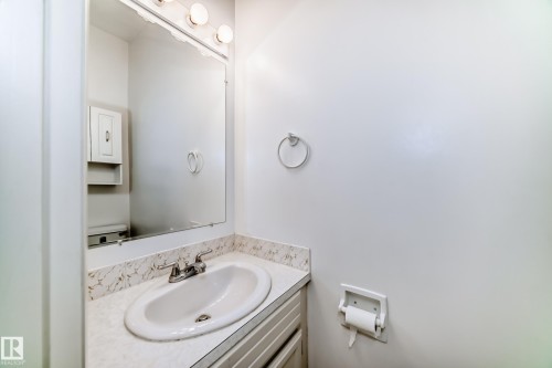 Bathroom vanity featuring a white oval sink, chrome faucet, and a patterned countertop - 14123 96 Street, Edmonton, AB 