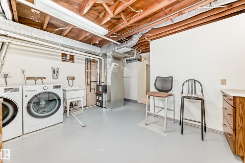 Utility area featuring a laundry hookup, white utility sink, exposed ceiling joists, white painted walls, and light gray flooring - 14123 96 Street, Edmonton, AB 