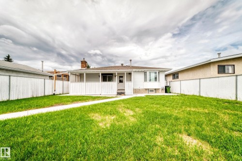 Expansive backyard featuring a lush lawn, concrete pathway, and chain-link fencing - 14123 96 Street, Edmonton, AB 