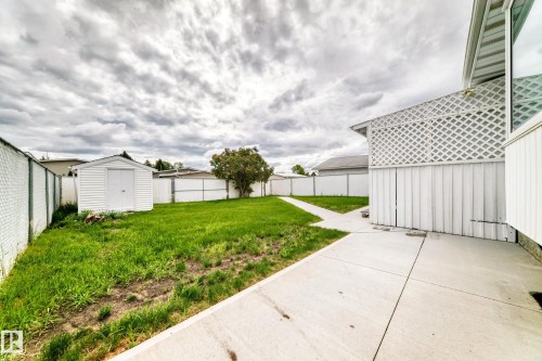 Expansive backyard featuring a concrete patio, additional storage shed, and a concrete pathway - 14123 96 Street, Edmonton, AB 