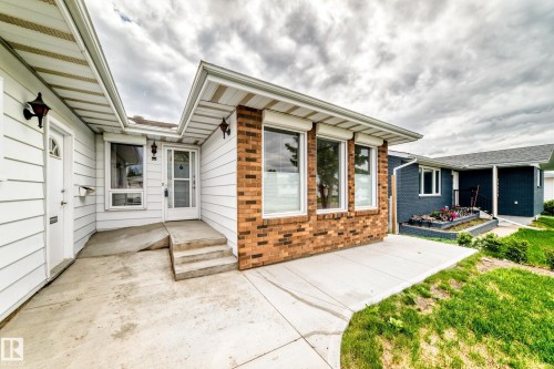 Exterior featuring white horizontal siding and a red brick accent wall - 14123 96 Street, Edmonton, AB 