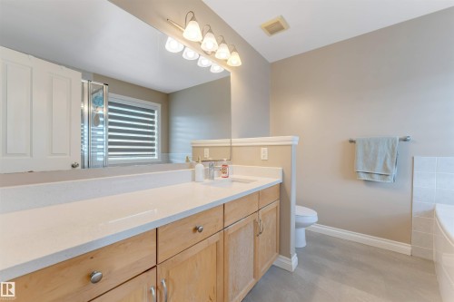 Bathroom featuring a light wood-finish vanity with a white countertop and double integrated sinks - 121 64 Street, Edmonton, AB - Indoor Photo Showing Bathroom
