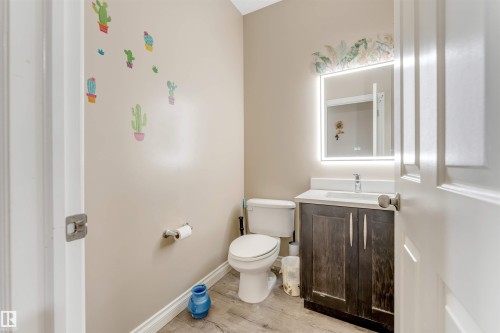 Bathroom with a dark wood-finish vanity, white countertop, and an illuminated mirror - 121 64 Street, Edmonton, AB - Indoor Photo Showing Bathroom