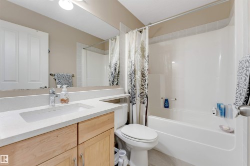 Contemporary bathroom featuring a light wood-finish vanity with a white countertop and integrated rectangular sink - 121 64 Street, Edmonton, AB - Indoor Photo Showing Bathroom