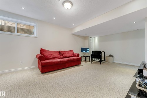 Spacious lower level featuring light-colored carpeting, a single egress window, recessed lighting, and a white paneled door - 121 64 Street, Edmonton, AB - Indoor