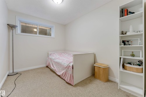 Carpeted room featuring a white-trimmed window, a flush-mount ceiling light, and a built-in shelving unit - 121 64 Street, Edmonton, AB - Indoor Photo Showing Bedroom