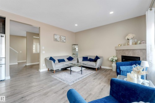 Living area featuring wood-finish flooring, a fireplace with a tiled surround and mantel, recessed lighting, and a wide entryway - 121 64 Street, Edmonton, AB - Indoor Photo Showing Living Room With Fireplace