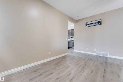 Open concept room featuring wood-finish flooring, light neutral wall tones, and white baseboards - 121 64 Street, Edmonton, AB - Indoor Photo Showing Other Room