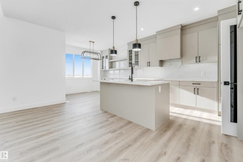 Open concept kitchen and living area featuring light-toned flooring, an island with a sink and faucet, and overhead lighting - 4102 67 Street, Beaumont, AB - Indoor Photo Showing Kitchen With Upgraded Kitchen