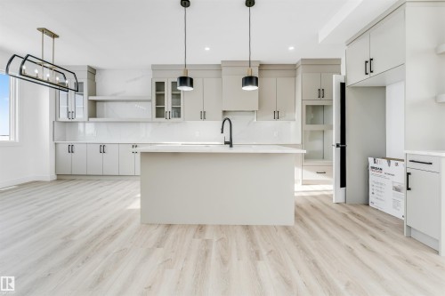 The kitchen features light-colored cabinetry with dark hardware, a center island with a black faucet, and pendant lighting - 4102 67 Street, Beaumont, AB - Indoor Photo Showing Kitchen With Upgraded Kitchen