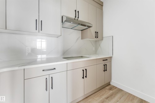 Kitchen featuring light-toned cabinetry with dark hardware, white countertops, and a matching white backsplash - 4102 67 Street, Beaumont, AB - Indoor Photo Showing Other Room
