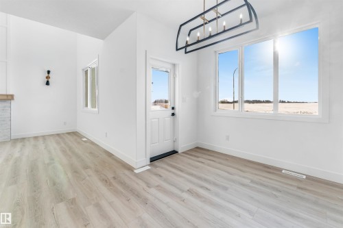 Open concept interior featuring light-toned flooring, white walls, and large windows that provide abundant natural light - 4102 67 Street, Beaumont, AB - Indoor Photo Showing Other Room