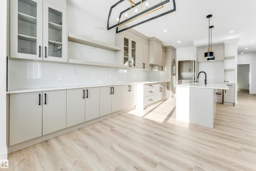 Modern kitchen featuring light-colored cabinetry, a spacious island with a sink, and light wood-style flooring - 4102 67 Street, Beaumont, AB - Indoor Photo Showing Kitchen With Upgraded Kitchen