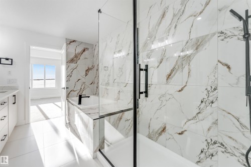 Luxurious bathroom featuring a spacious shower with glass enclosure, a built-in bathtub, and elegant marble-style wall tiling - 4102 67 Street, Beaumont, AB - Indoor Photo Showing Bathroom