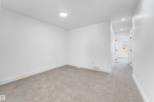 This room features light-colored carpeting, white walls, and a circular flush mount light fixture - 4102 67 Street, Beaumont, AB - Indoor Photo Showing Other Room