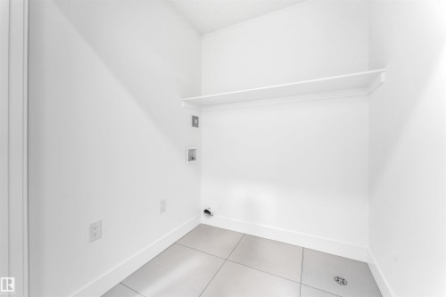 The property features a utility room with a white shelf, white walls, and light-colored tiled flooring - 4102 67 Street, Beaumont, AB - Indoor Photo Showing Other Room