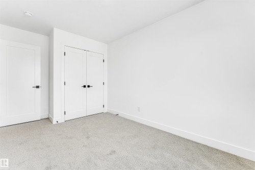 This room features light-colored carpeting, white walls, white doors with black hardware, and a white ceiling - 4102 67 Street, Beaumont, AB - Indoor Photo Showing Other Room