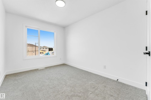 This room features light-colored carpeting, white walls, and a window with a white frame - 4102 67 Street, Beaumont, AB - Indoor Photo Showing Other Room
