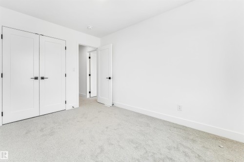 The room features light-colored carpeting, white walls, and white doors with dark hardware - 4102 67 Street, Beaumont, AB - Indoor Photo Showing Other Room